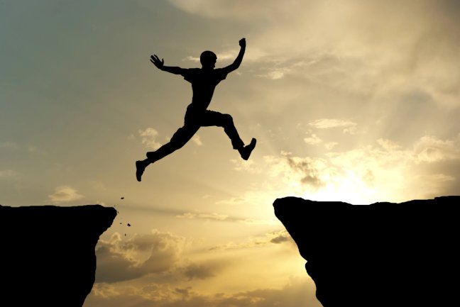 man jumping on rock columns